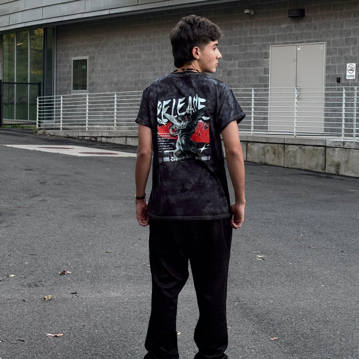 Person wearing a black t-shirt with graphic design standing on a street.