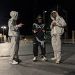Two people in matching outfits standing on a street at night.