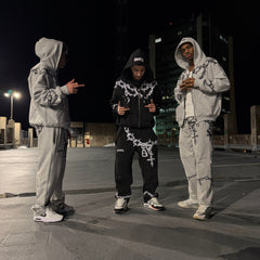 Two people in matching outfits standing on a street at night.