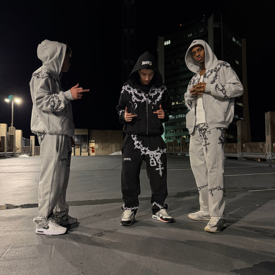 Two people in matching outfits standing on a street at night.