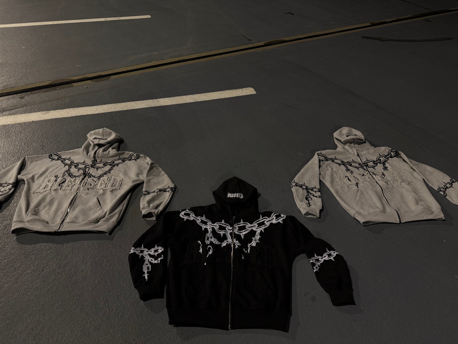 Three hoodies with decorative elements on a dark surface