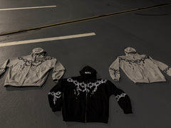 Three hoodies with decorative elements on a dark surface