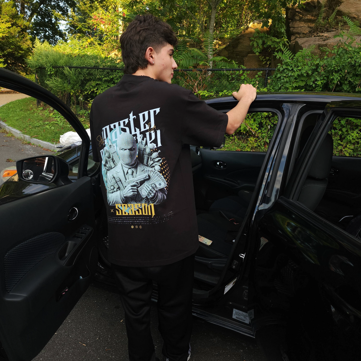 Person getting into a car wearing a black t-shirt with graphic design