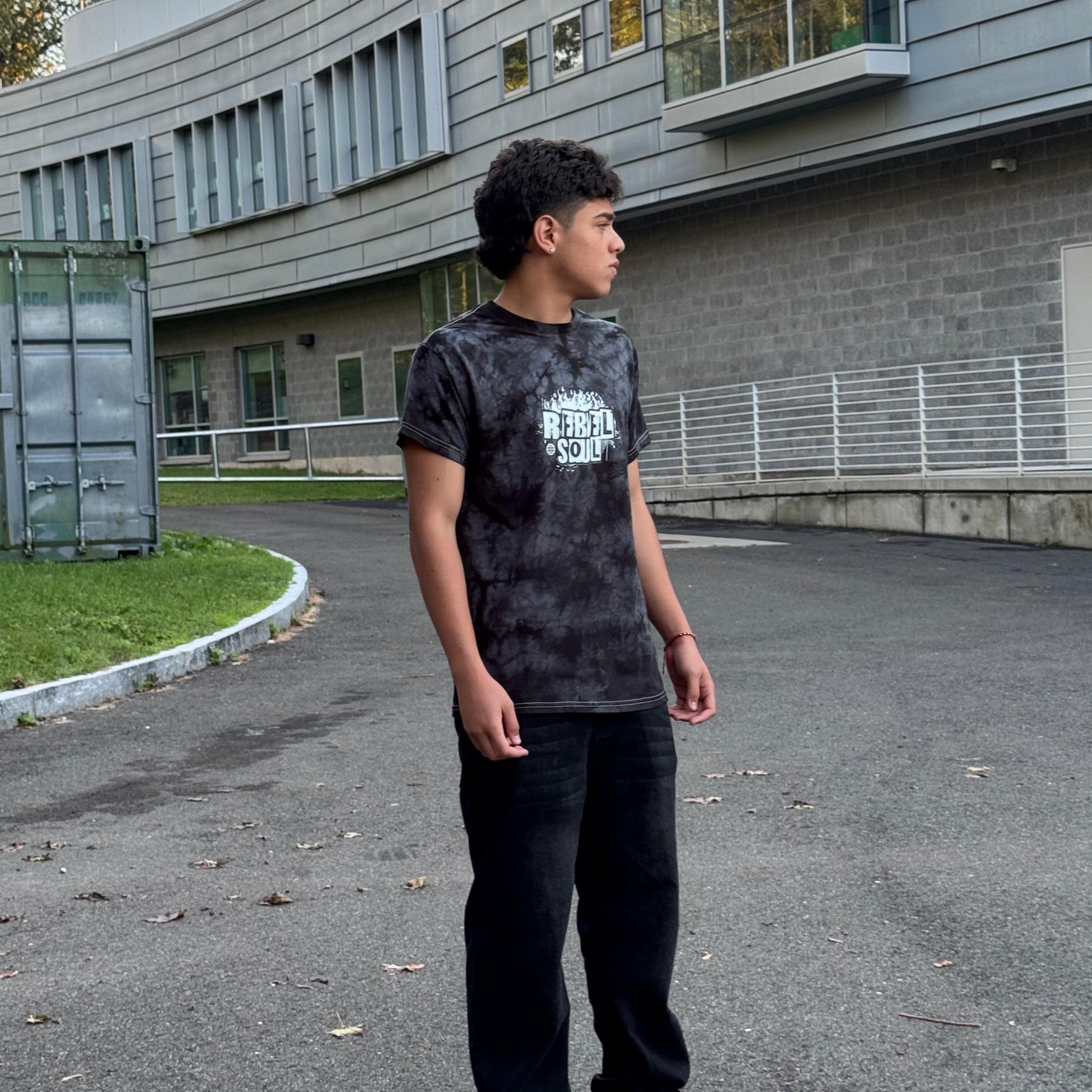 Young boy standing on a paved area in front of a building